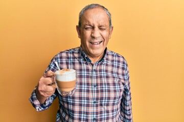 Handsome senior man with grey hair drinking a cup coffee winking looking at the camera with sexy...