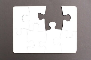 White jigsaw puzzles assembled on a gray background with a chipped piece