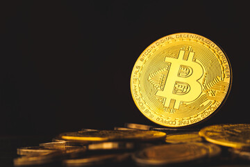 Selective focus of golden bitcoins on dark background with a pile of gold coins. concept of  investing in cryptocurrency.