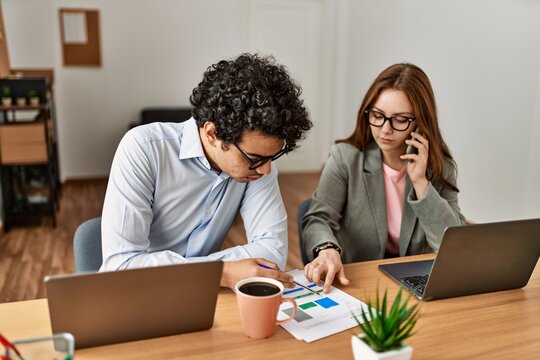 Two business workers with serious expression working and talking on the smartphone at the office.