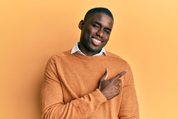 Young african american man wearing casual clothes cheerful with a smile of face pointing with hand and finger up to the side with happy and natural expression on face