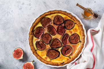 Homemade quiche tart with figs, cream cheese and honey on light wooden background. Vintage style....