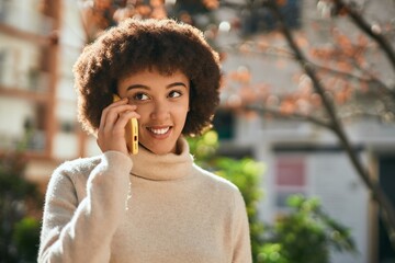 Fototapeta premium Young hispanic girl smiling happy using smartphone at the city.