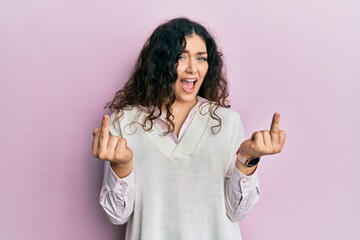 Young brunette woman with curly hair wearing casual clothes showing middle finger doing fuck you...