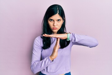 Young hispanic woman wearing casual clothes doing time out gesture with hands, frustrated and serious face
