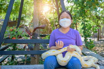 Young girl wear mask and hold an albino python, pet