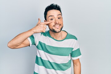 Young hispanic man wearing casual clothes pointing with hand finger to face and nose, smiling cheerful. beauty concept