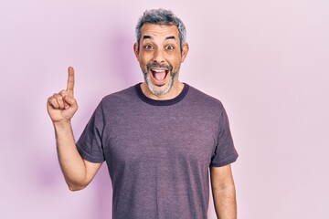 Handsome middle age man with grey hair pointing with index finger celebrating crazy and amazed for...