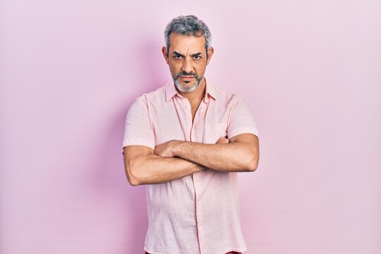 Handsome middle age man with grey hair wearing casual shirt skeptic and nervous, disapproving expression on face with crossed arms. negative person.