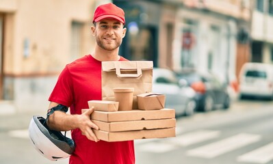 Young caucasian deliveryman smiling happy holding delivery food at the city.