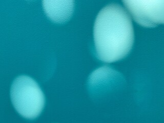 Blurred circle lights on teal green wall background, glowing lights on blue wall.  Copy space for your work.