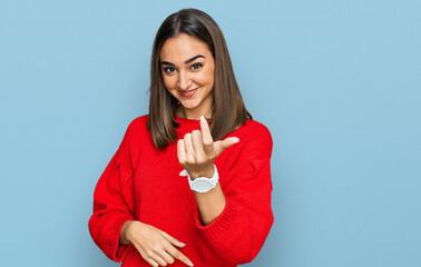 Beautiful brunette woman wearing casual winter sweater beckoning come here gesture with hand inviting welcoming happy and smiling