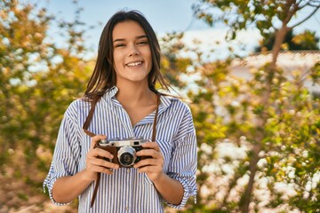 Young hispanic tourist girl smiling happy using camera at the park