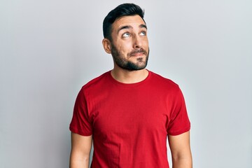 Young hispanic man wearing casual clothes smiling looking to the side and staring away thinking.