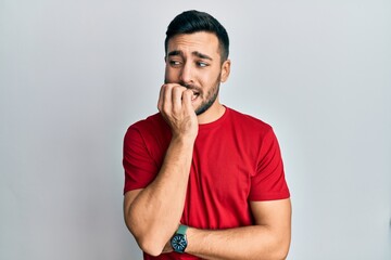 Young hispanic man wearing casual clothes looking stressed and nervous with hands on mouth biting nails. anxiety problem.