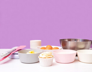 Ingredients for making cupcakes with a ready-made cake. Side view. Lilac background with space for text. Selective focus.
