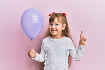 Little caucasian girl kid holding purple balloon smiling with an idea or question pointing finger with happy face, number one - Powered by Adobe