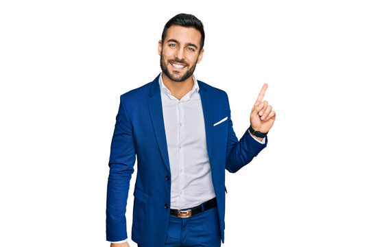 Young hispanic man wearing business jacket with a big smile on face, pointing with hand finger to the side looking at the camera.