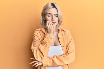 Young blonde girl wearing casual clothes looking stressed and nervous with hands on mouth biting nails. anxiety problem. - obrazy, fototapety, plakaty