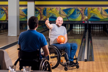 Two young disabled men in wheelchairs playing bowling in the club