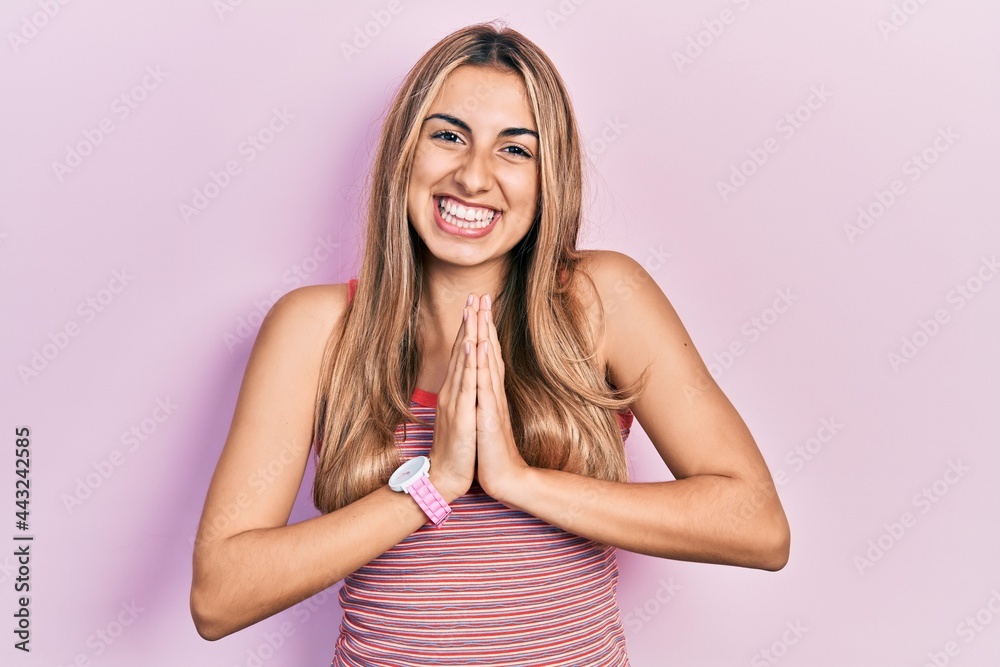 Poster Beautiful hispanic woman wearing casual summer t shirt praying with hands together asking for forgiveness smiling confident.