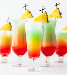 Close up of colourful cocktails with pineapple wedges, ready for drinking.