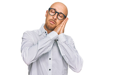 Bald man with beard wearing business shirt and glasses sleeping tired dreaming and posing with hands together while smiling with closed eyes.