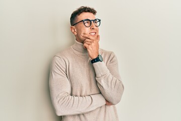 Hispanic young man wearing casual turtleneck sweater thinking worried about a question, concerned and nervous with hand on chin