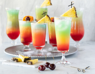 A tray of colourful mocktails with one out in front, ready for drinking.