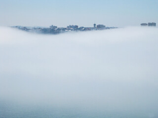 Panorámica de la ciudad de A Coruña en la que se observa como la niebla, sobre el mar, va dejando ver parte de los edificios herculinos
