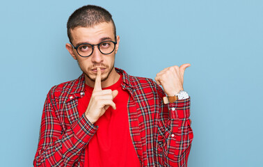 Hispanic young man wearing casual clothes asking to be quiet with finger on lips pointing with hand...