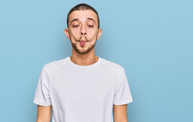 Hispanic young man wearing casual white t shirt making fish face with lips, crazy and comical gesture. funny expression.