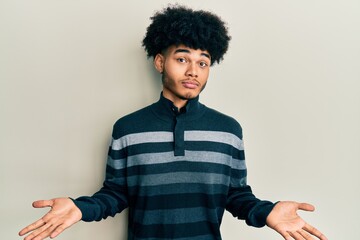 Young african american man with afro hair wearing casual clothes clueless and confused expression...