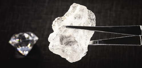 rough diamond or crystal held by a jeweler's tweezers, with jewels in the background, spot focus