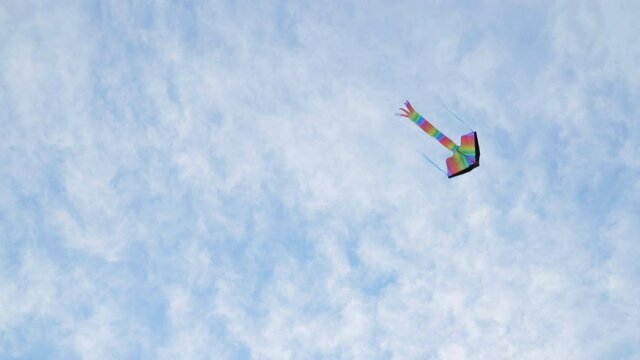 4K Footage of a flying multicolored rainbow style new kids toy in the blue sky. Active outdoor concept image.