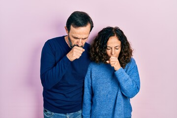 Middle age couple of hispanic woman and man hugging and standing together feeling unwell and coughing as symptom for cold or bronchitis. health care concept.