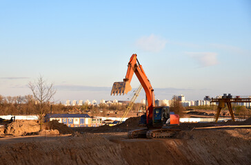 Excavator digging foundation at construction site. Heavy machinery for groungwork. House...