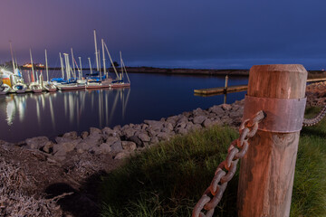 Obraz premium Wodden posts hold the large chain links firmly in place as a barrier around the Ventura marina water.