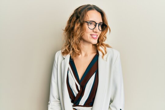 Young caucasian woman wearing business style and glasses looking away to side with smile on face, natural expression. laughing confident.
