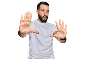 Fototapeta premium Young man with beard wearing casual white t shirt doing stop gesture with hands palms, angry and frustration expression