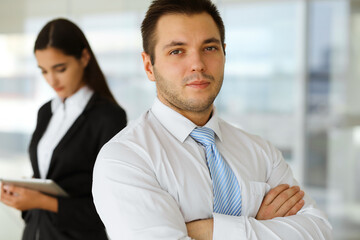 Portrait of a self-confident middle-aged businessman, standing with his colleague in the background in a modern office. Business concept