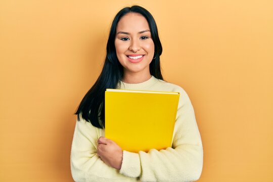 Beautiful hispanic woman with nose piercing holding book smiling with a happy and cool smile on face. showing teeth.