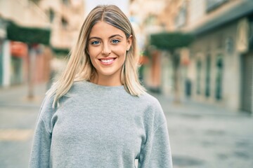 Young blonde girl smiling happy standing at the city. - obrazy, fototapety, plakaty