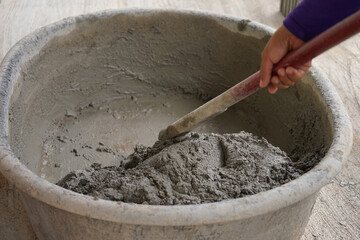 workers use spade mixing wet cement in cement mixing basin, selective focus