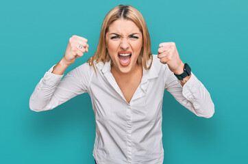 Young caucasian woman wearing casual clothes angry and mad raising fists frustrated and furious...