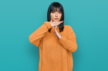 Young hispanic woman wearing casual clothes doing time out gesture with hands, frustrated and...