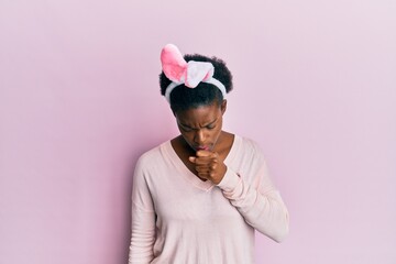 Young african american girl wearing cute easter bunny ears feeling unwell and coughing as symptom for cold or bronchitis. health care concept.