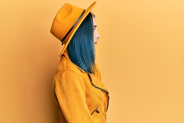 Young modern girl wearing yellow hat and leather jacket looking to side, relax profile pose with...