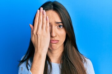 Young hispanic girl covering half face with hand depressed and worry for distress, crying angry and...