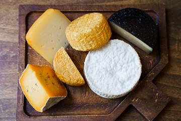 assorted cheese heads on cutting board on wooden table. cheese factory.